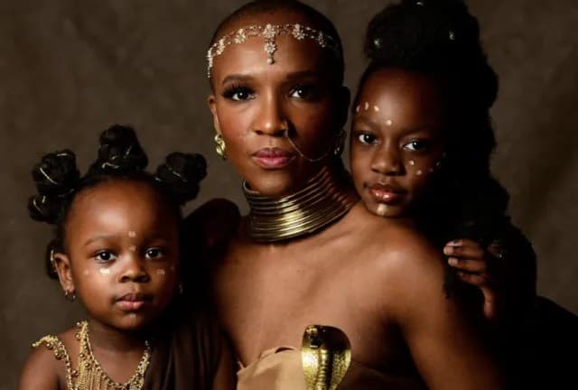 A motherly Black woman with two Black kids dressed like royalty